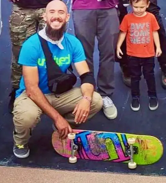 Coach Evan crouching with a young child and a graffiti-style skateboard